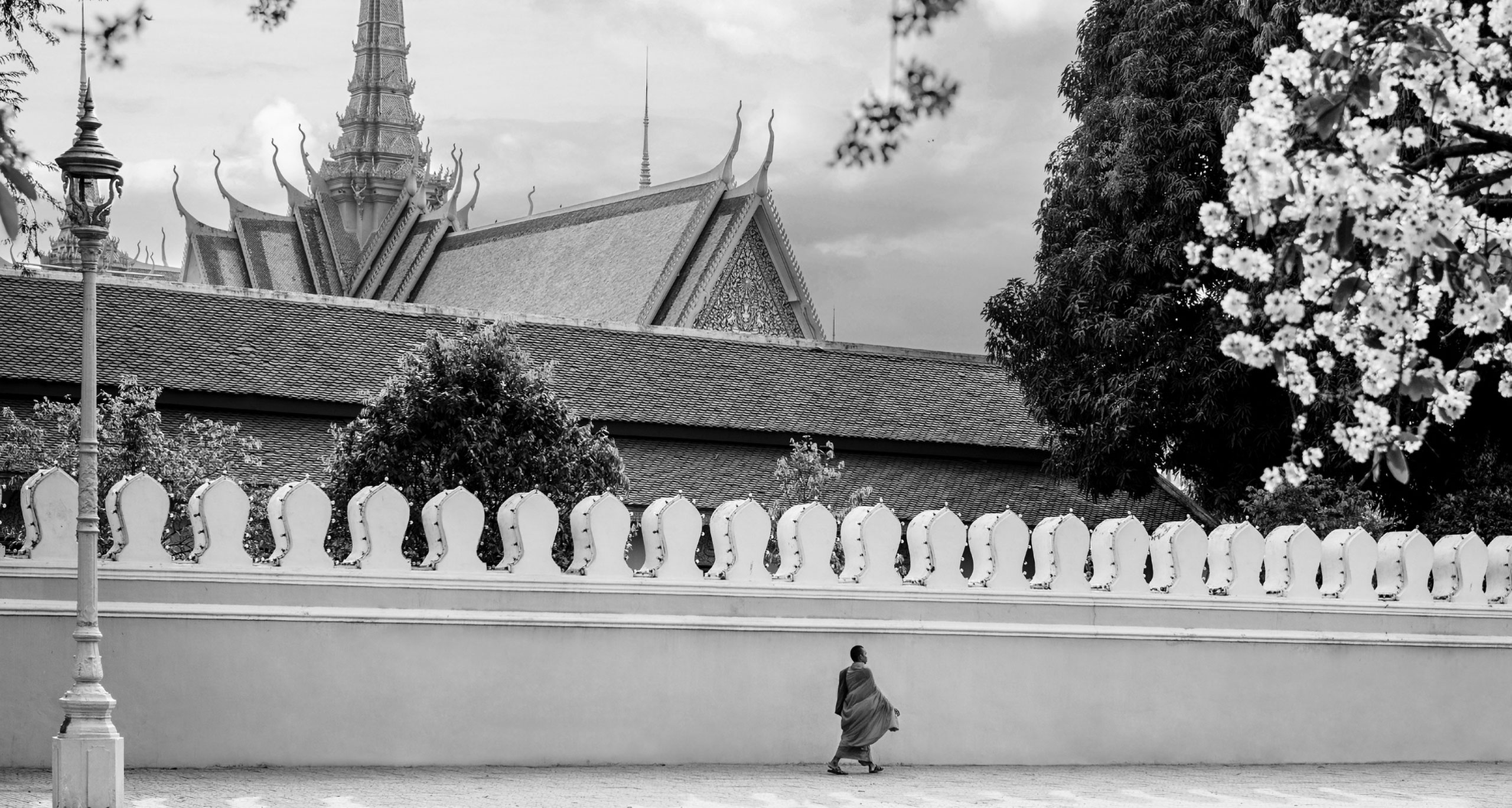 A monk walking outside the Royal Palace Throne Hall in Phnom Penh, creating a serene and spiritual scene